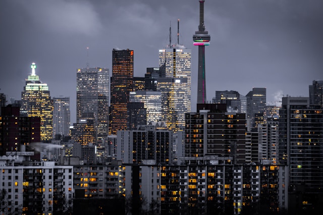Pros of Buying a Rental Property in Toronto | Manage Your Property Nighttime skyline of a city with illuminated windows; CN Tower stands among tall buildings.