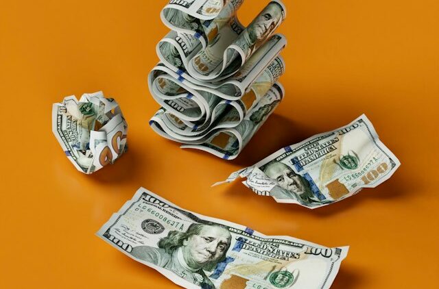 Rent Roll- A Tenant-by-Tenant Revenue View | Manage Your Property Crumpled and loose US dollar bills scattered on an orange surface, conveying money or wastefulness in a financial context.
