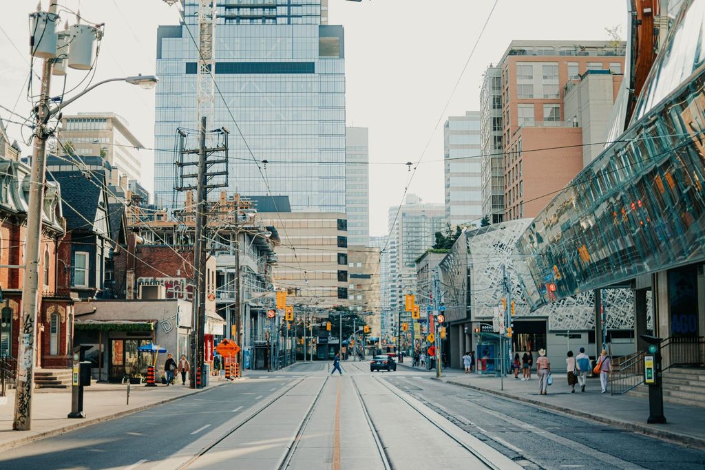 image | Manage Your Property Urban street scene with tram tracks running down the center, overhead wires, and a mix of brick town houses and modern glass high-rises.